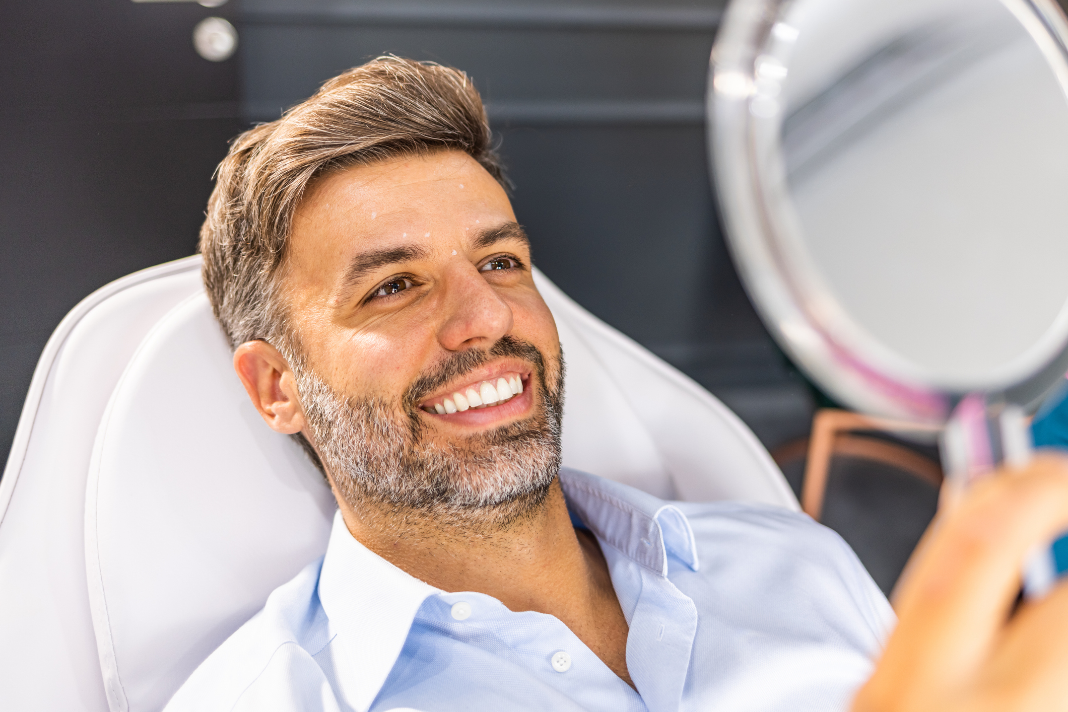 Middle aged man reviewing wrinkles in hand mirror after botulinum toxin